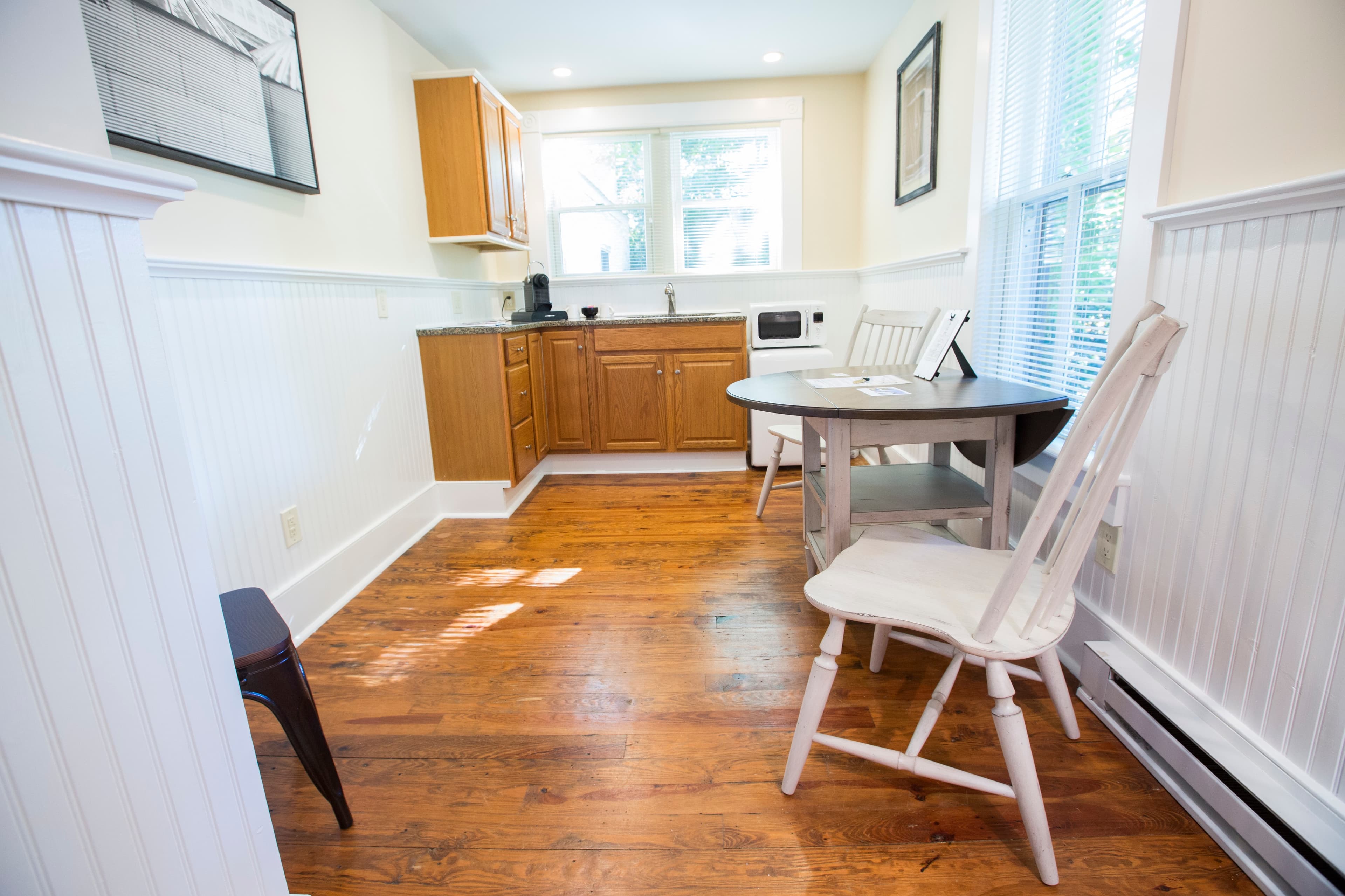 Bright kitchen with wooden floors, a small table, and cabinetry.