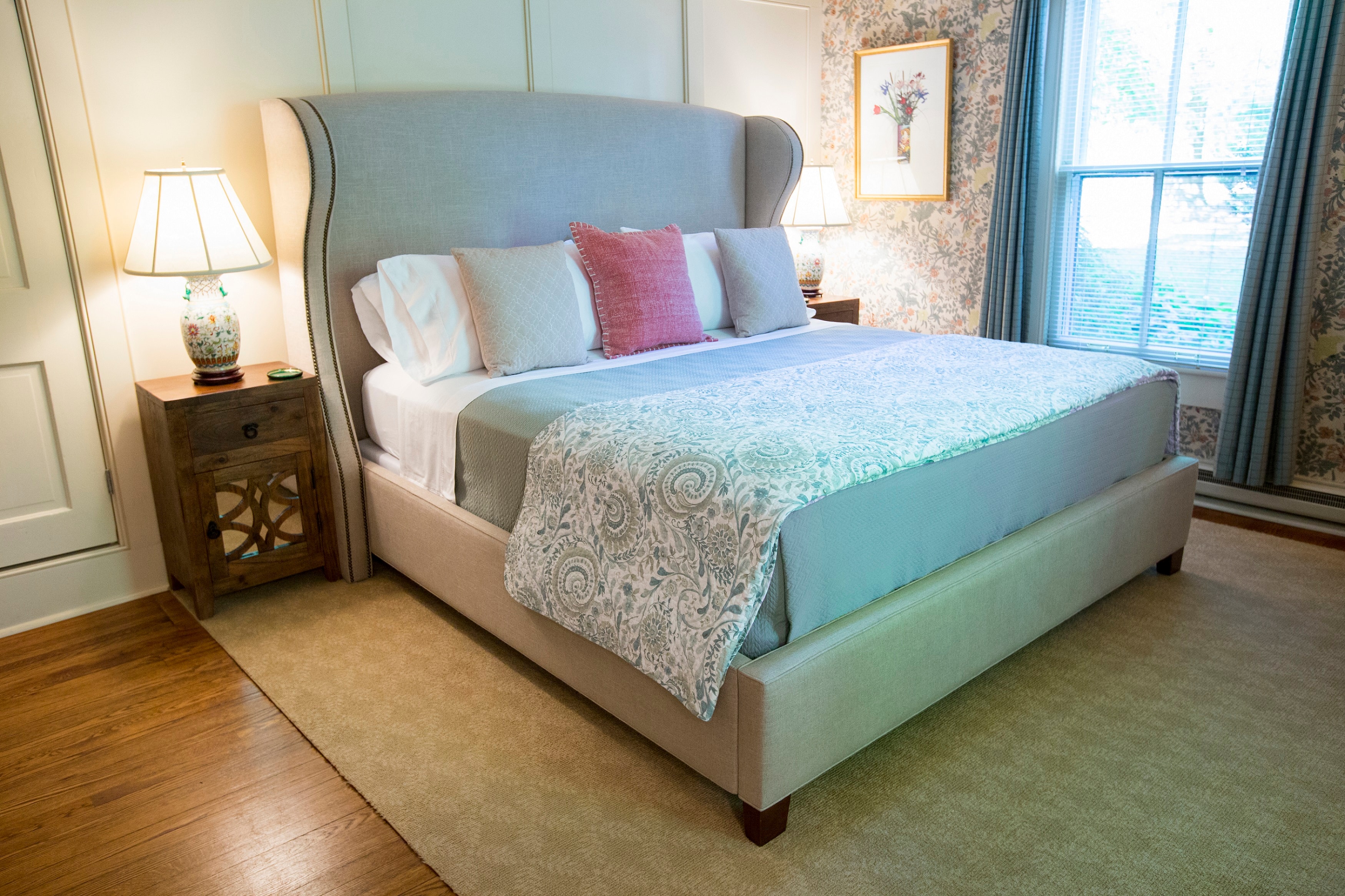 A neatly made bed with decorative pillows in a cozy, well-lit bedroom.