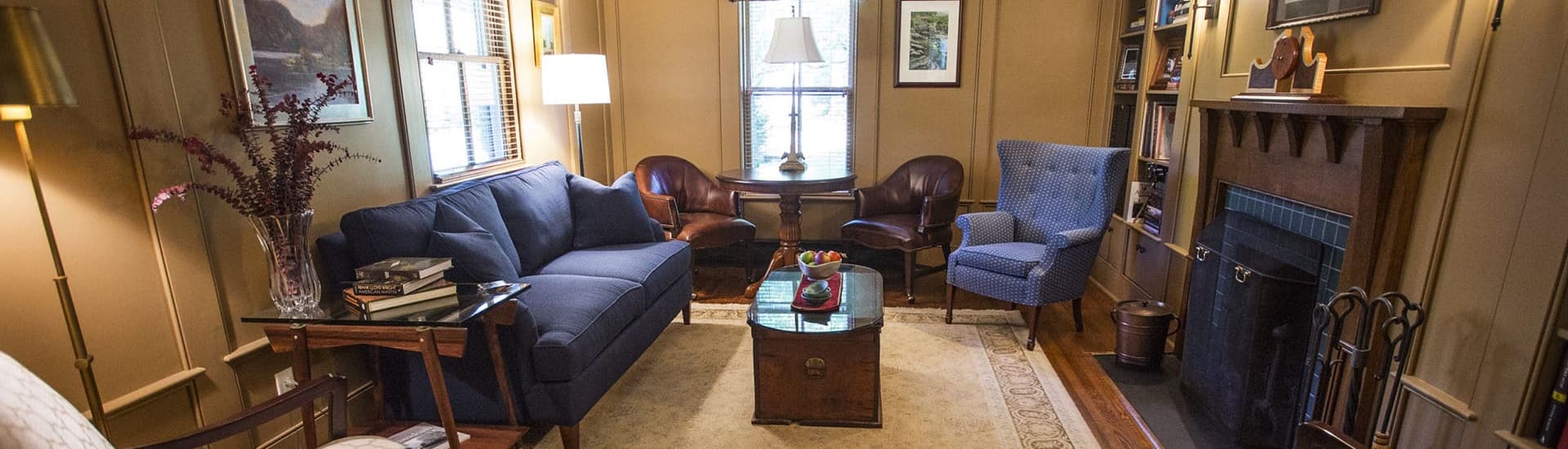 A cozy living room features a blue sofa, wooden furniture, and a decorative fireplace.