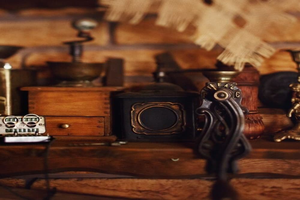A close-up of assorted vintage objects on a wooden shelf, including a drawer, a grinder, and various decorative items.