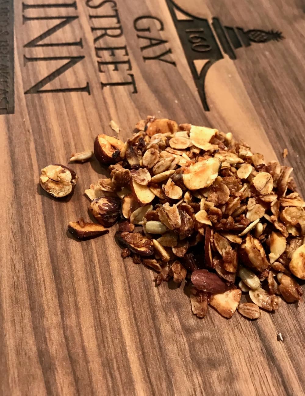 A small pile of granola mixes rests on a wooden surface engraved with "Gay Street Inn."