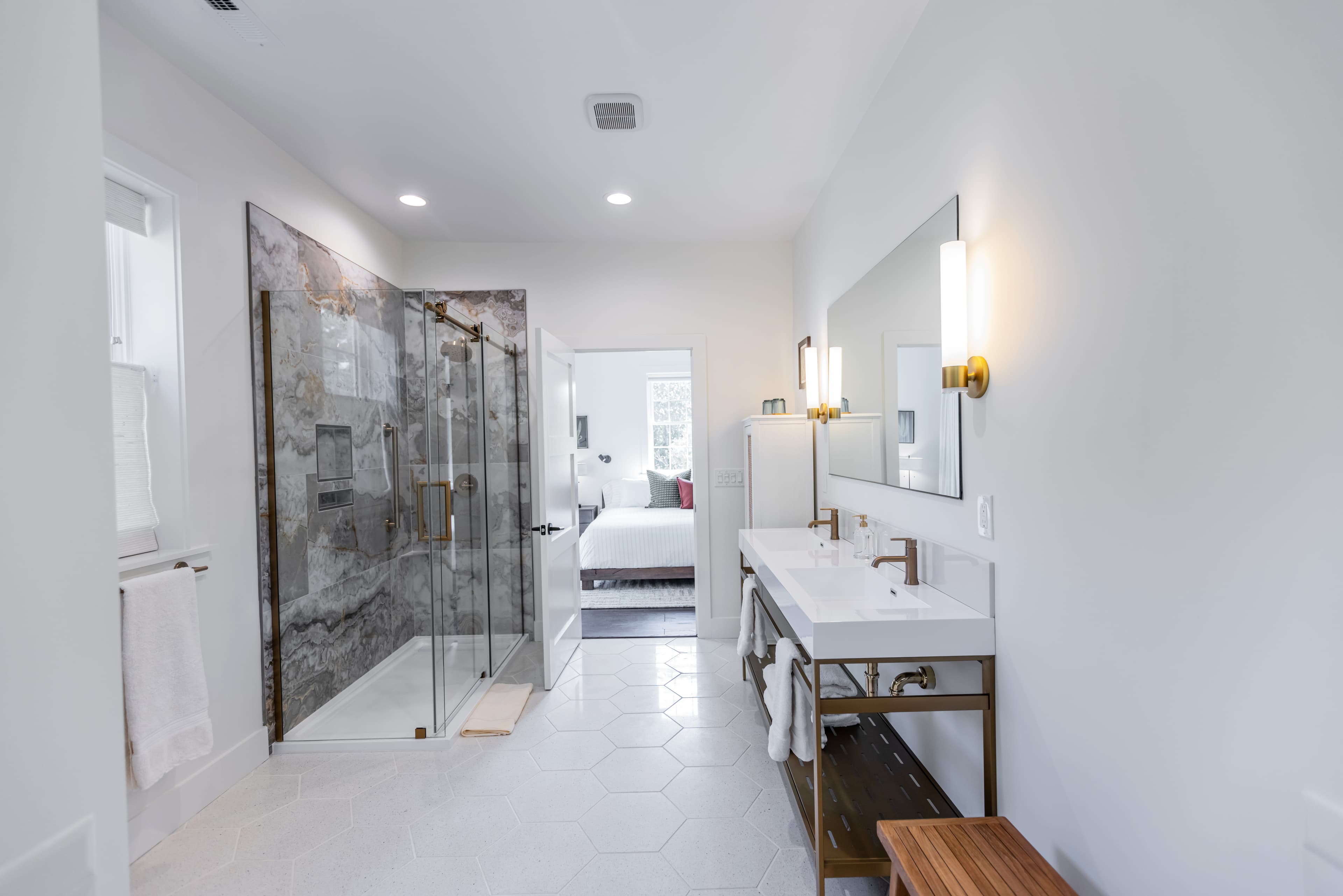 A modern bathroom featuring a glass shower, double vanity, and neutral decor.