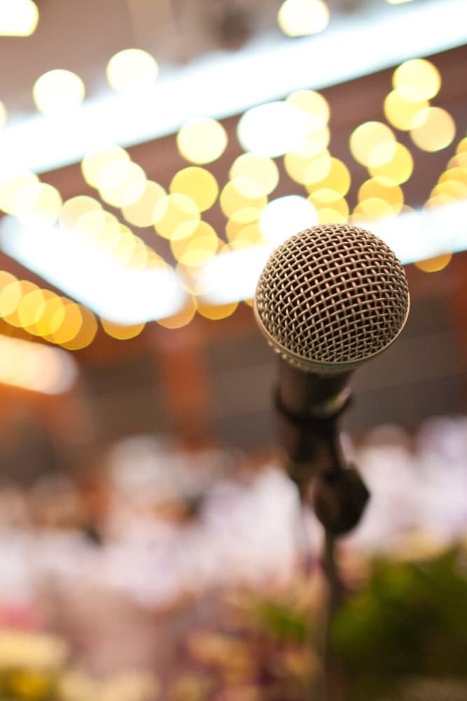 A close-up of a microphone with soft, blurred bokeh lights in the background.