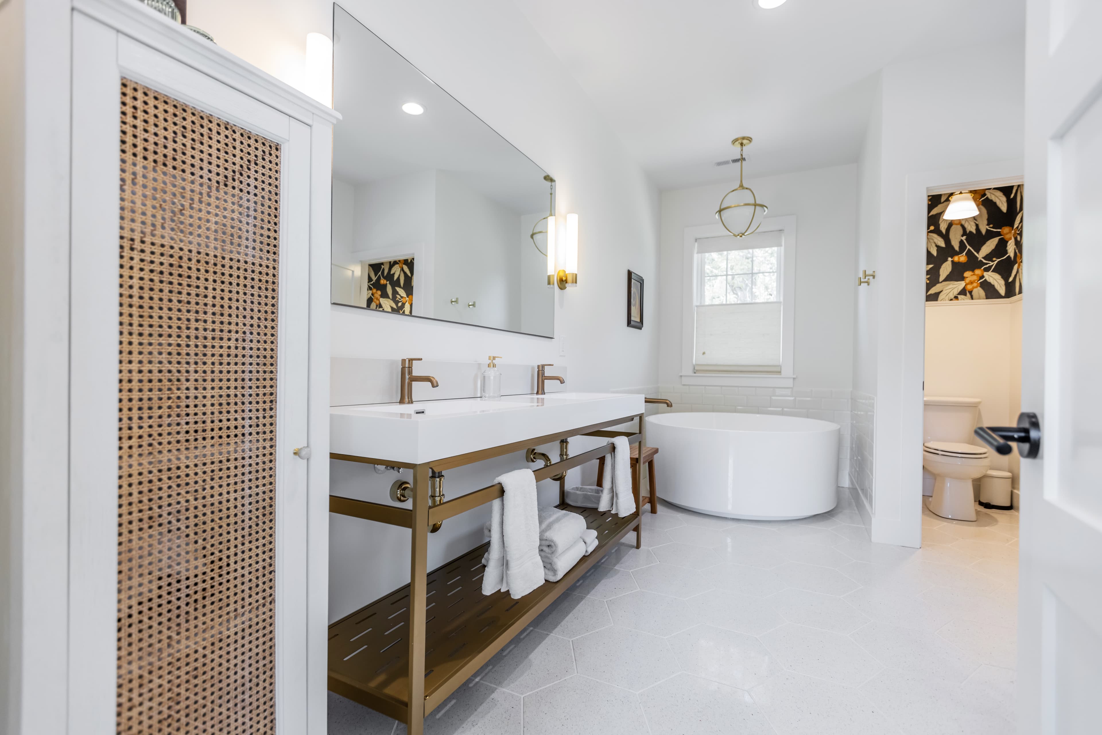 A modern bathroom featuring a double vanity with a large mirror, a freestanding bathtub, and stylish decor.
