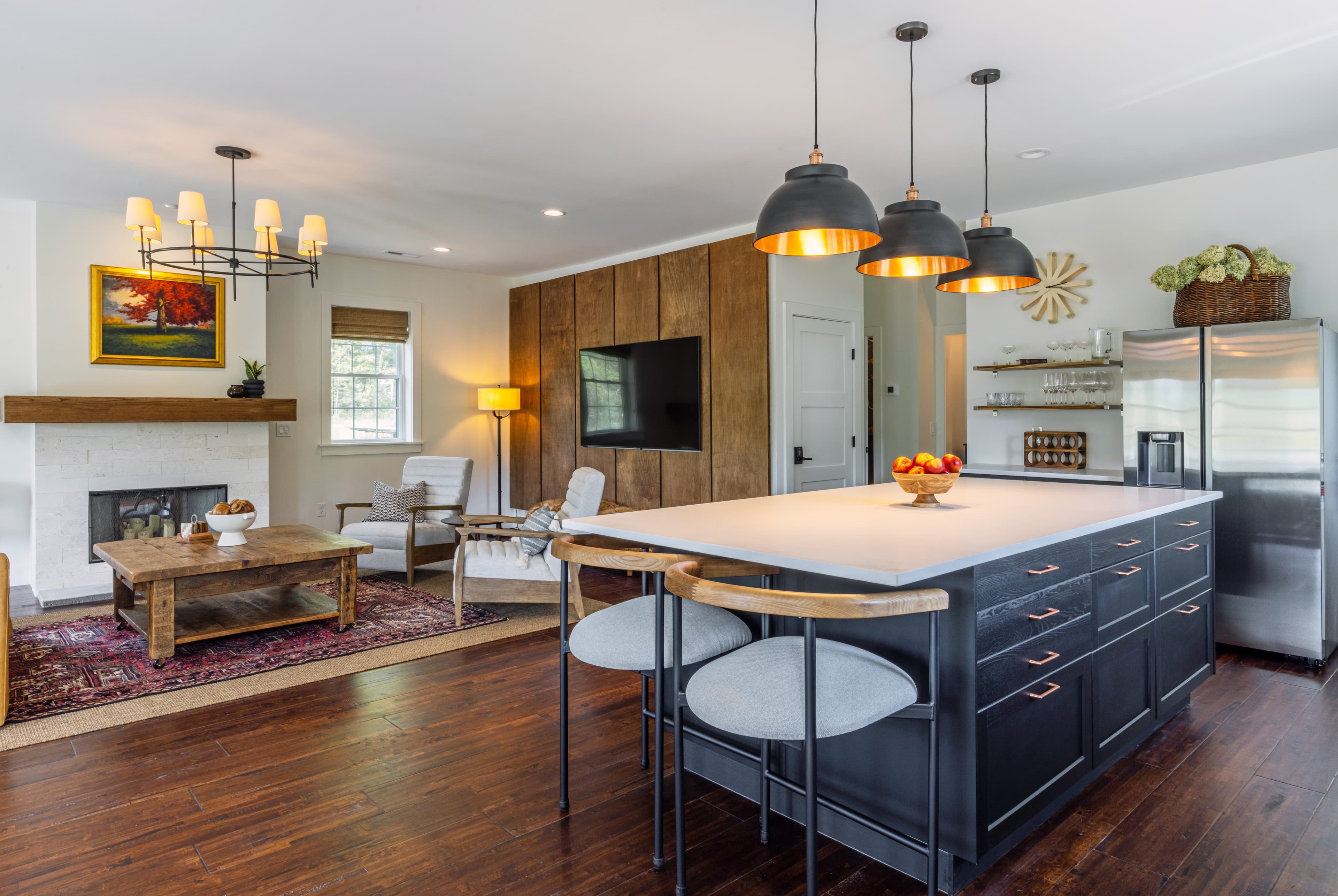 A modern open-concept kitchen and living area featuring a large island, wooden accents, and cozy seating.