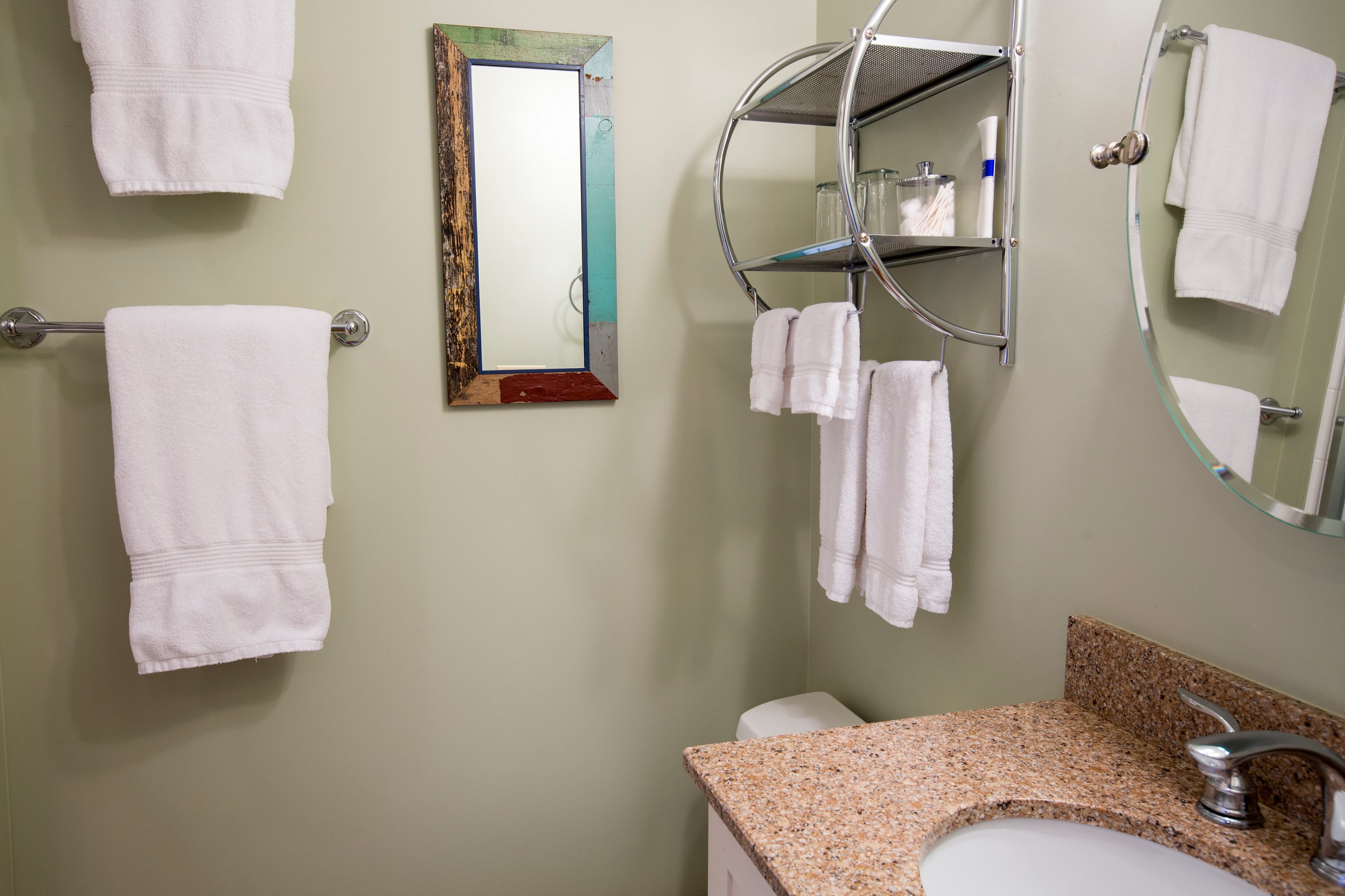 A clean bathroom featuring a sink, mirror, and neatly arranged white towels on the walls.