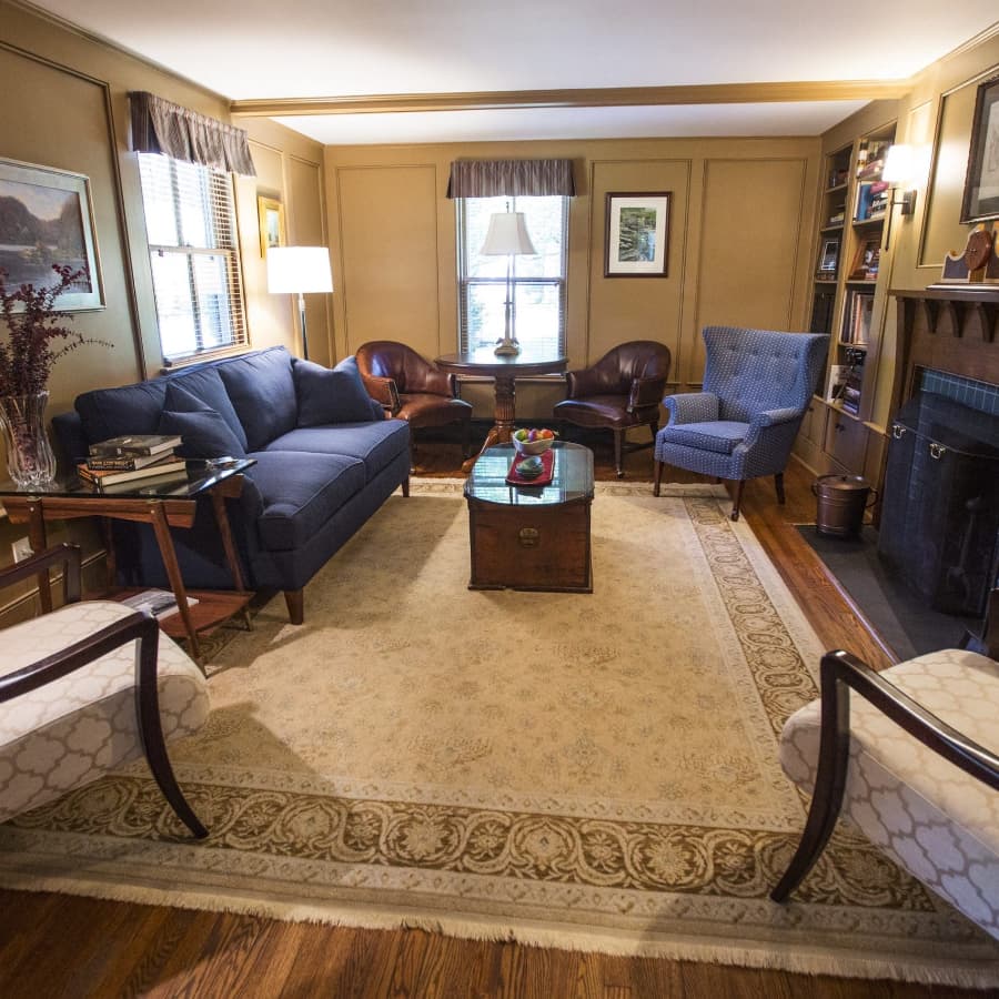 Cozy living room with a blue sofa, two armchairs, a coffee table, and a warm color palette.